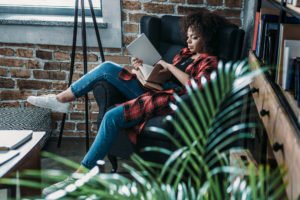 Black woman lounging in chair reading